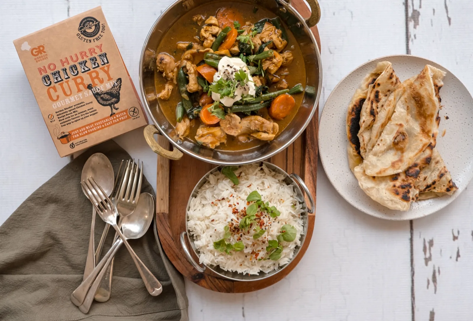 Gordon Rhodes No Hurry Chicken Curry sauce mix beside a karahi of chicken curry, basmati r