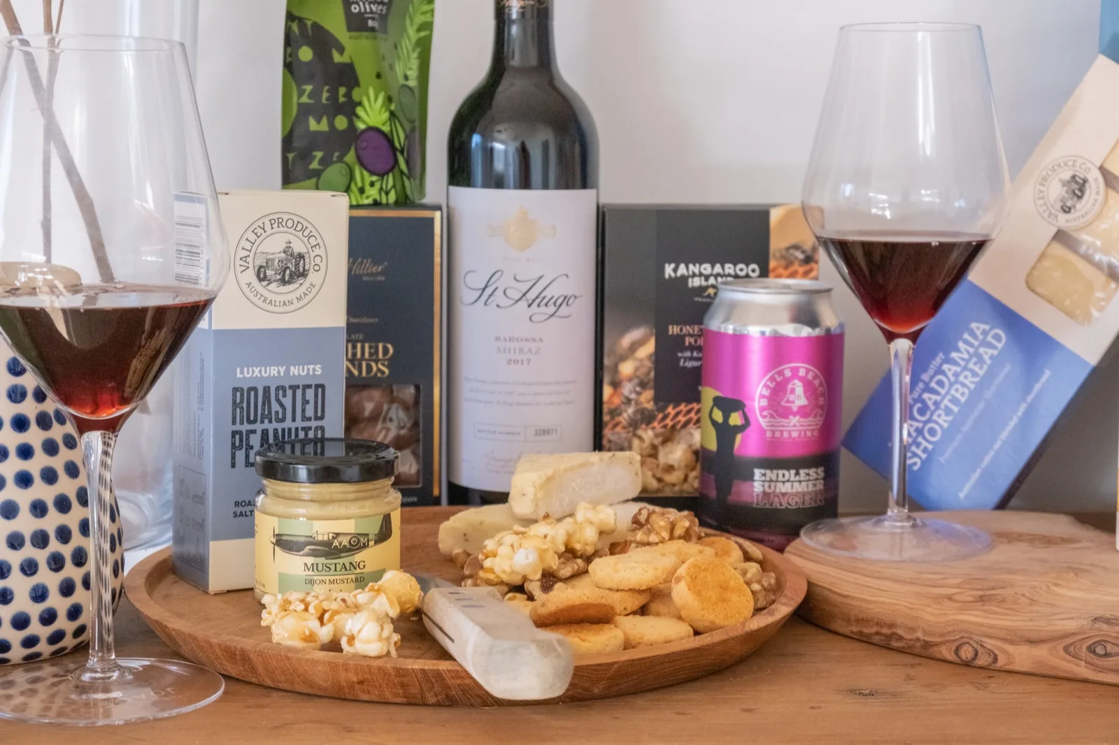 Roasted peanut and olive packs beside poured wine glasses and a plate of popcorn, walnuts 