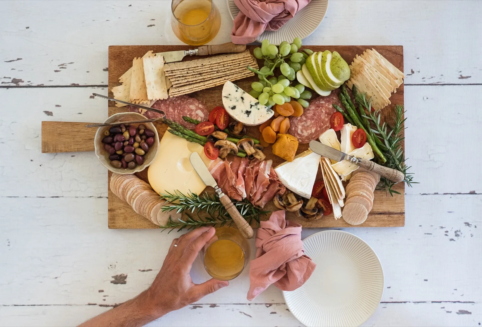 Overhead grazing board of crackers, olives, salami, brie, grapes and