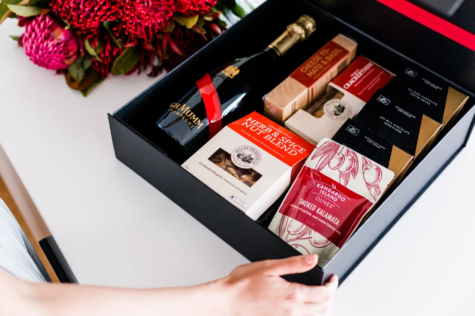 Open hamper from The Gourmet Pantry with artisan crackers, spiced nuts, kalamata olives and chocolate