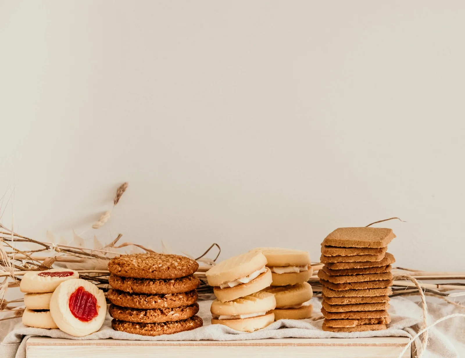 Stacks of jam drops, Anzac biscuits, custard creams and shortbread fingers on a linen lined board