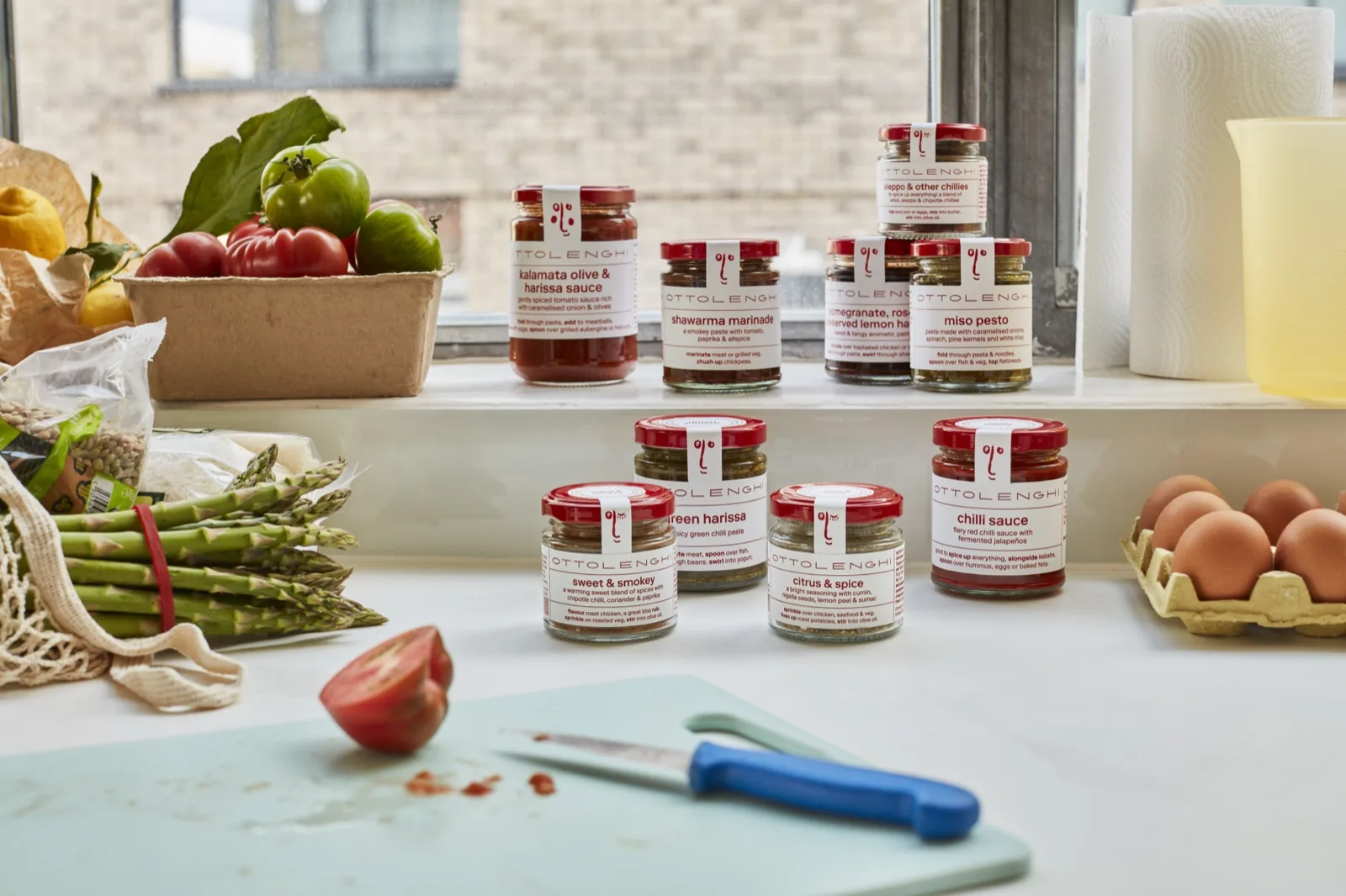 Ottolenghi green harissa, rose harissa and kalamata olive harissa jars lined up on a kitchen bench