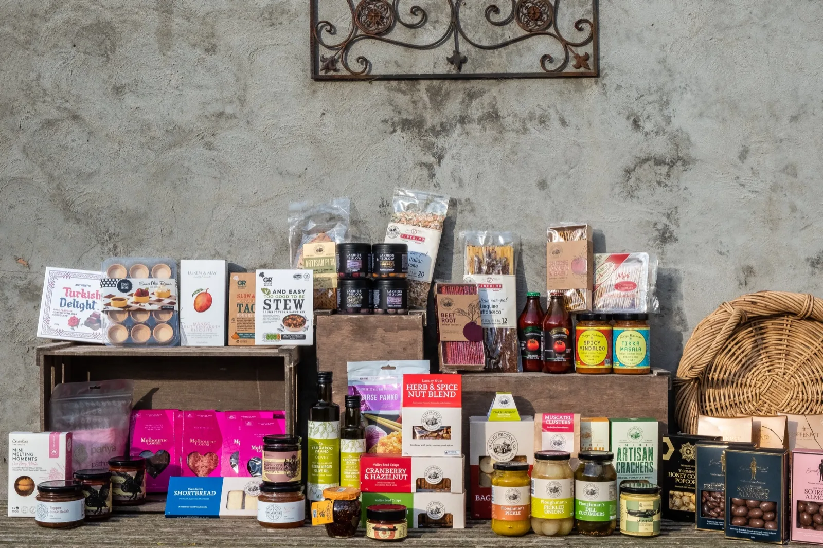 Wooden crates stacked with shelf stable pantry goods including biscuits, chutneys, pickles, crackers and choco