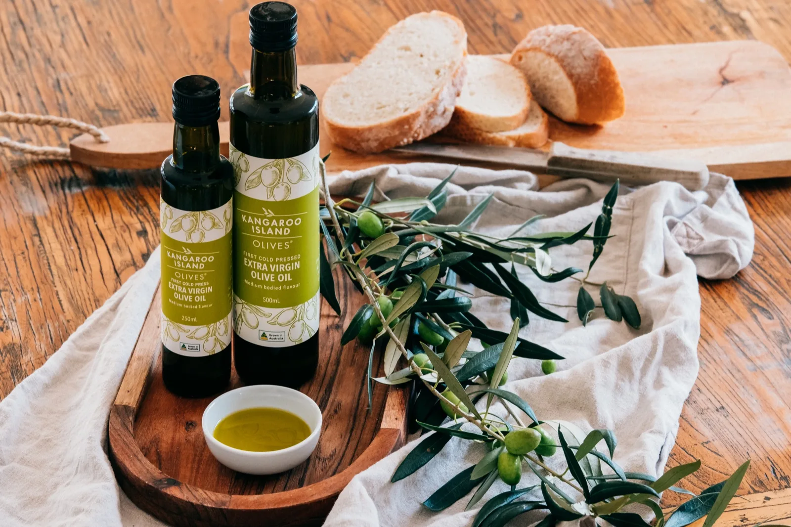 Kangaroo Island Olives extra virgin olive oil bottles with a dish of poured oil, olive spr