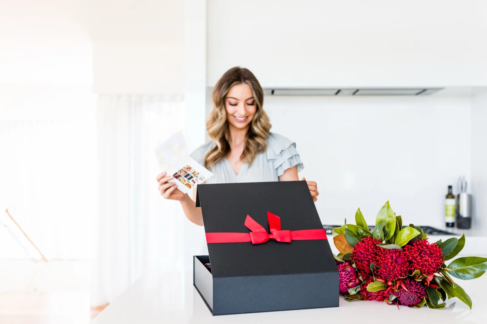 Opening a black Gourmet Pantry Christmas hamper and reading the gift card, red waratahs on