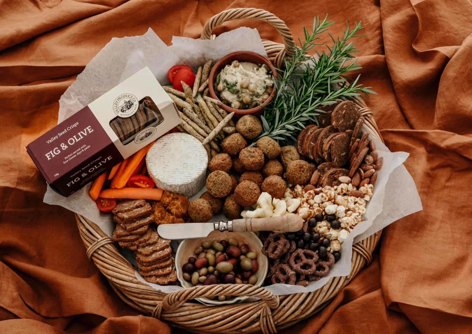 Grazing basket with olives, popcorn, pretzels, brie, seed crisps and crackers in separate 