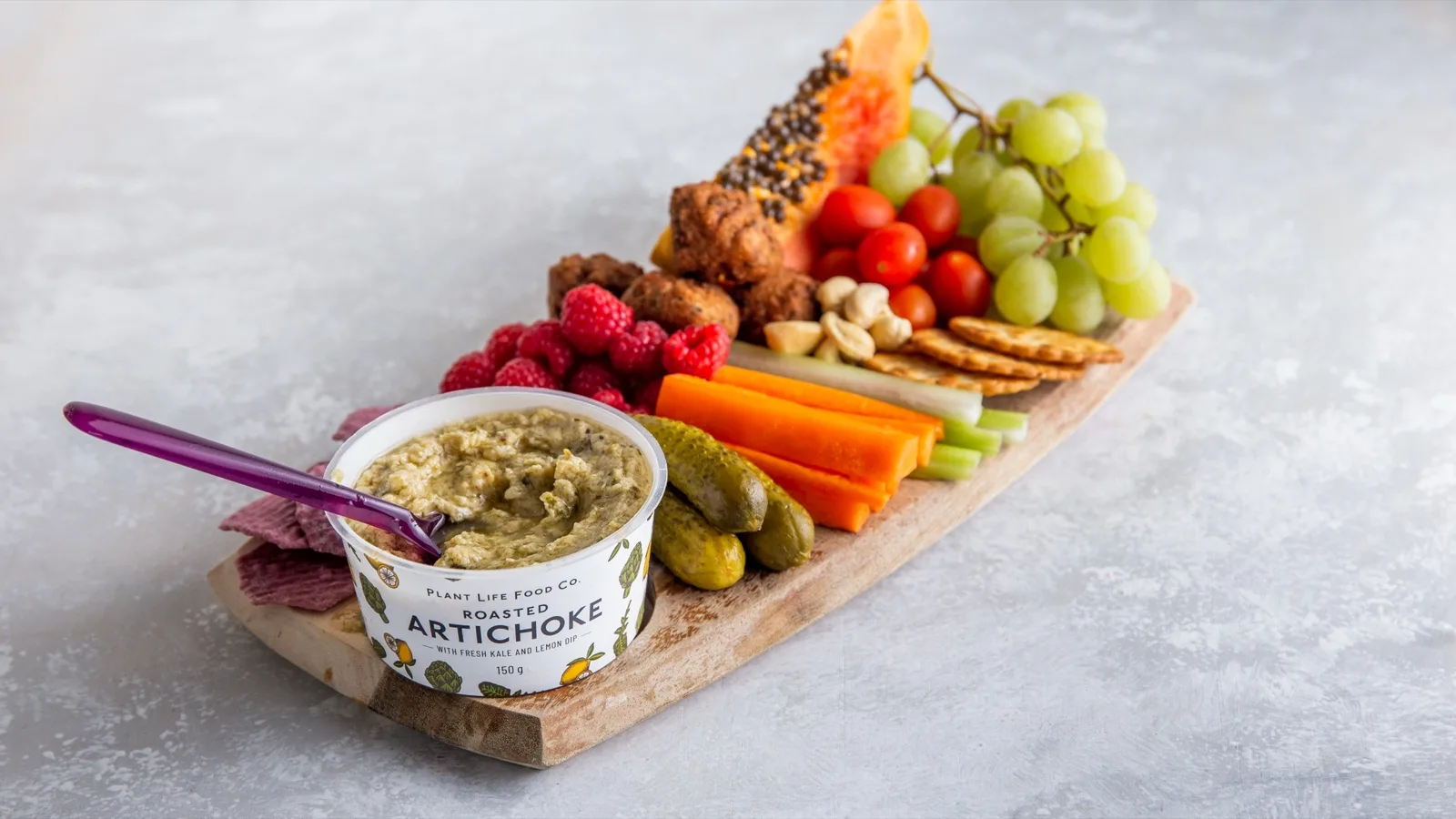 Plant Life Food Co roasted artichoke dip on a board with falafel, carrot and celery sticks