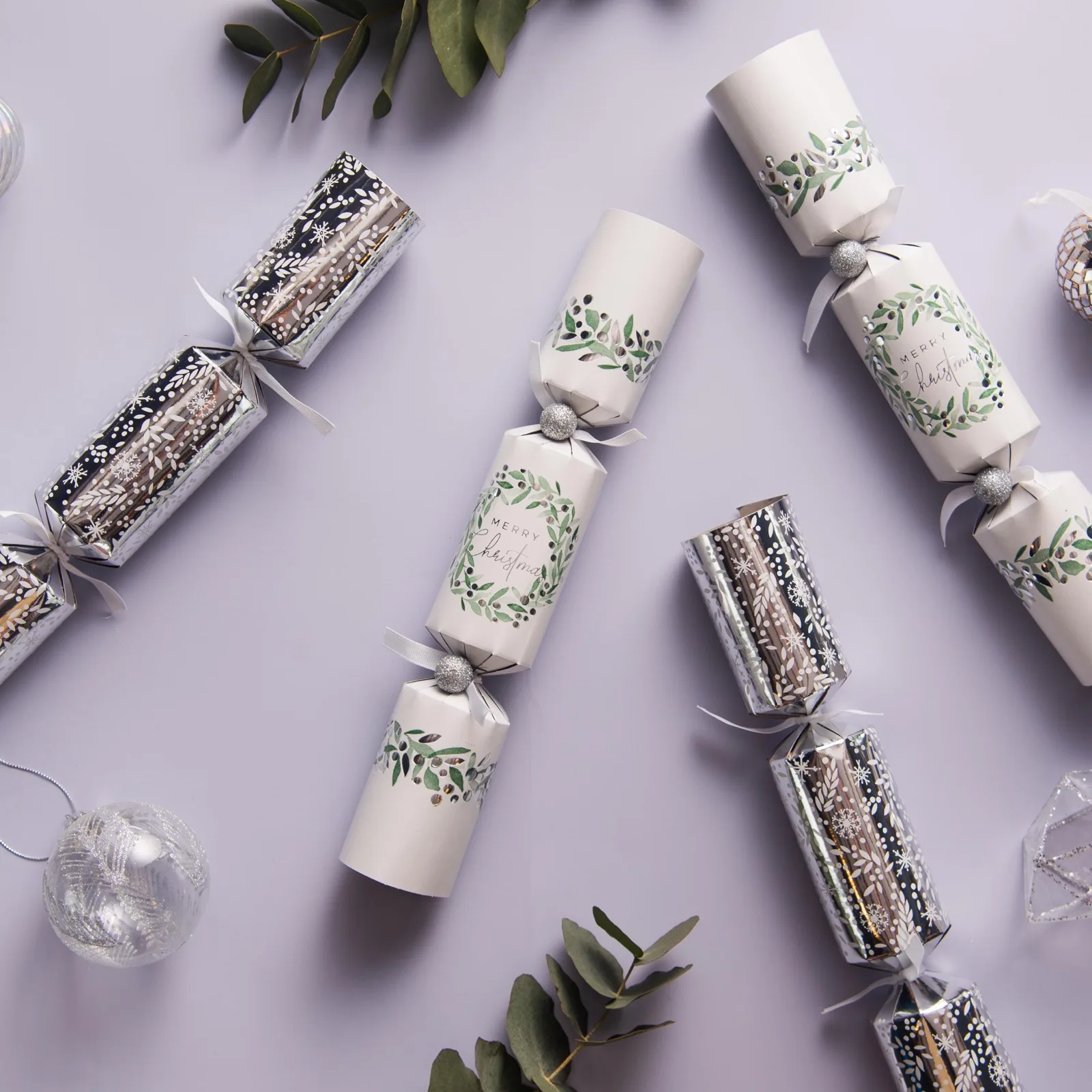 Christmas bon bon crackers in silver foil and Merry Christmas foliage prints with baubles and eucalyptus