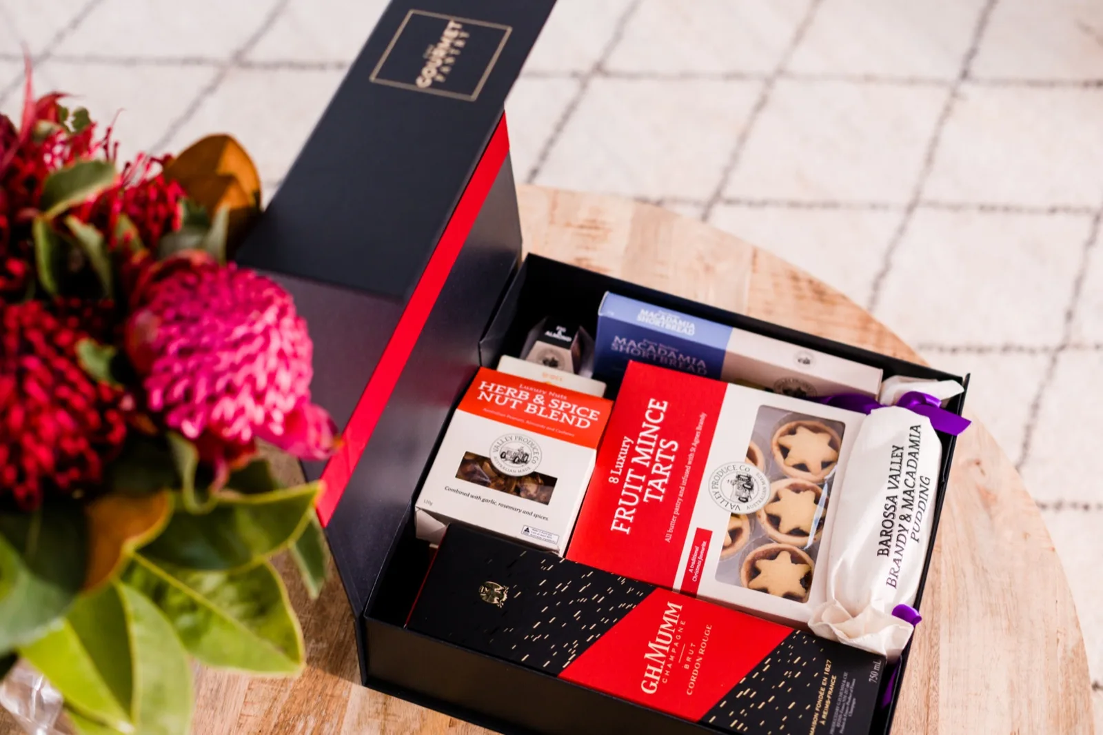 Christmas hamper open on a table with fruit mince tarts, brandy pudding, macadamia shortbr