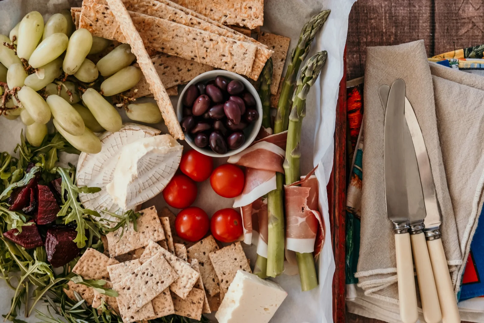 Seeded crispbreads and sesame crackers with brie, feta and kalamata olives on a board with cheese knives